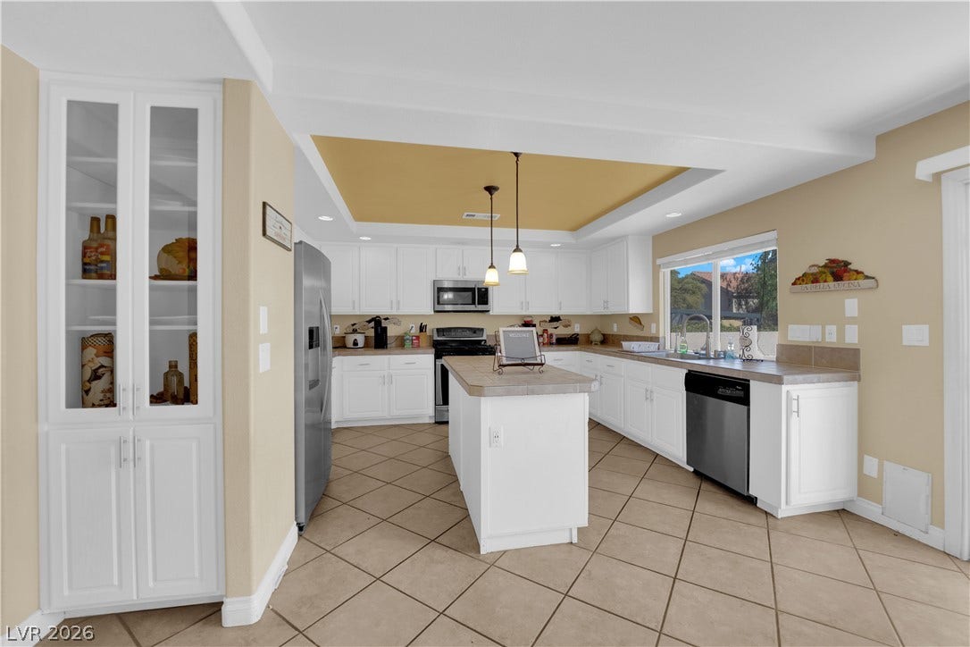 9852 Snowy Canyon Court, Las Vegas, NV 89183 Tiled floors and white cabinetry frame a kitchen centered around a functional prep island.