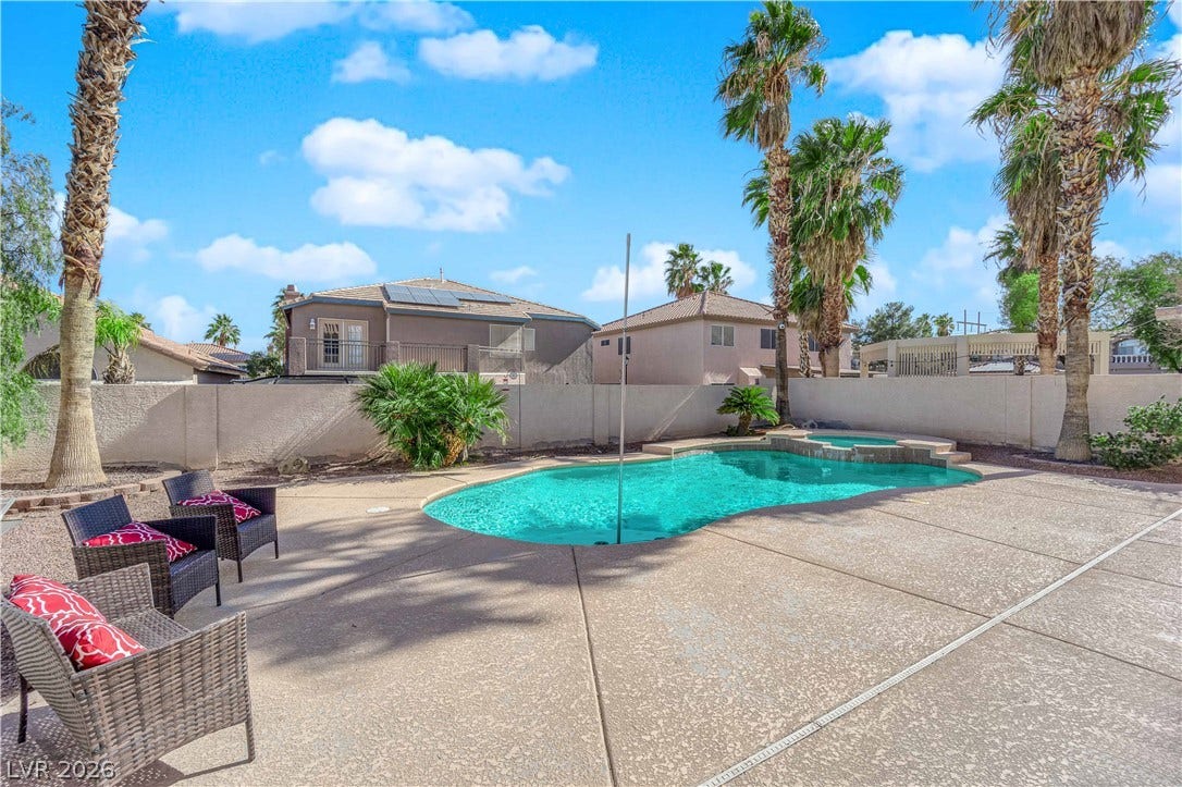 9852 Snowy Canyon Court, Las Vegas, NV 89183 Mature palm trees frame a private backyard swimming pool surrounded by spacious concrete decking.