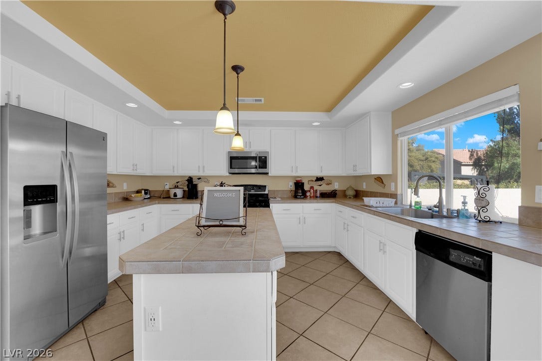 9852 Snowy Canyon Court, Las Vegas, NV 89183 White cabinetry stands out against tile countertops in this kitchen complete with a center island.