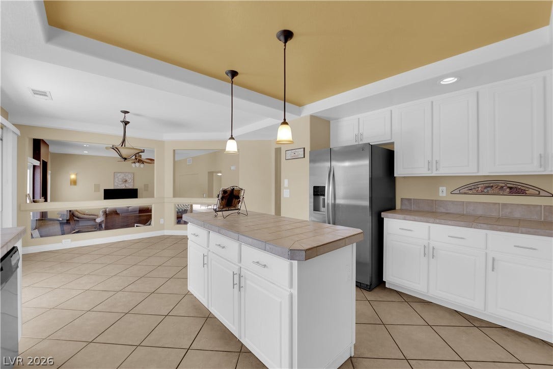 9852 Snowy Canyon Court, Las Vegas, NV 89183 Tiled flooring flows through a well-equipped kitchen featuring an island under a tray ceiling.