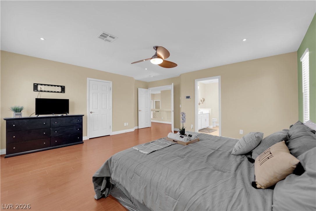 9852 Snowy Canyon Court, Las Vegas, NV 89183 Smooth wood floors and recessed lighting anchor this spacious primary bedroom suite.