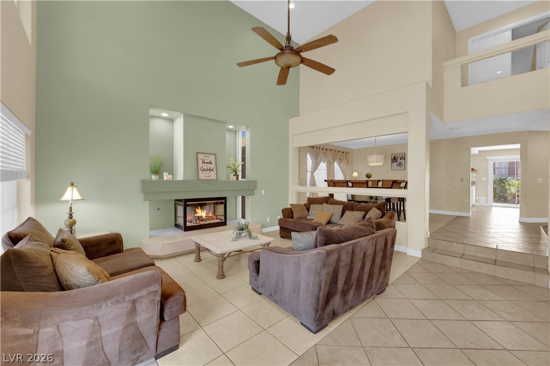 9852 Snowy Canyon Court, Las Vegas, NV 89183 Soaring ceilings and an elegant fireplace define this light-filled, open-concept living space.