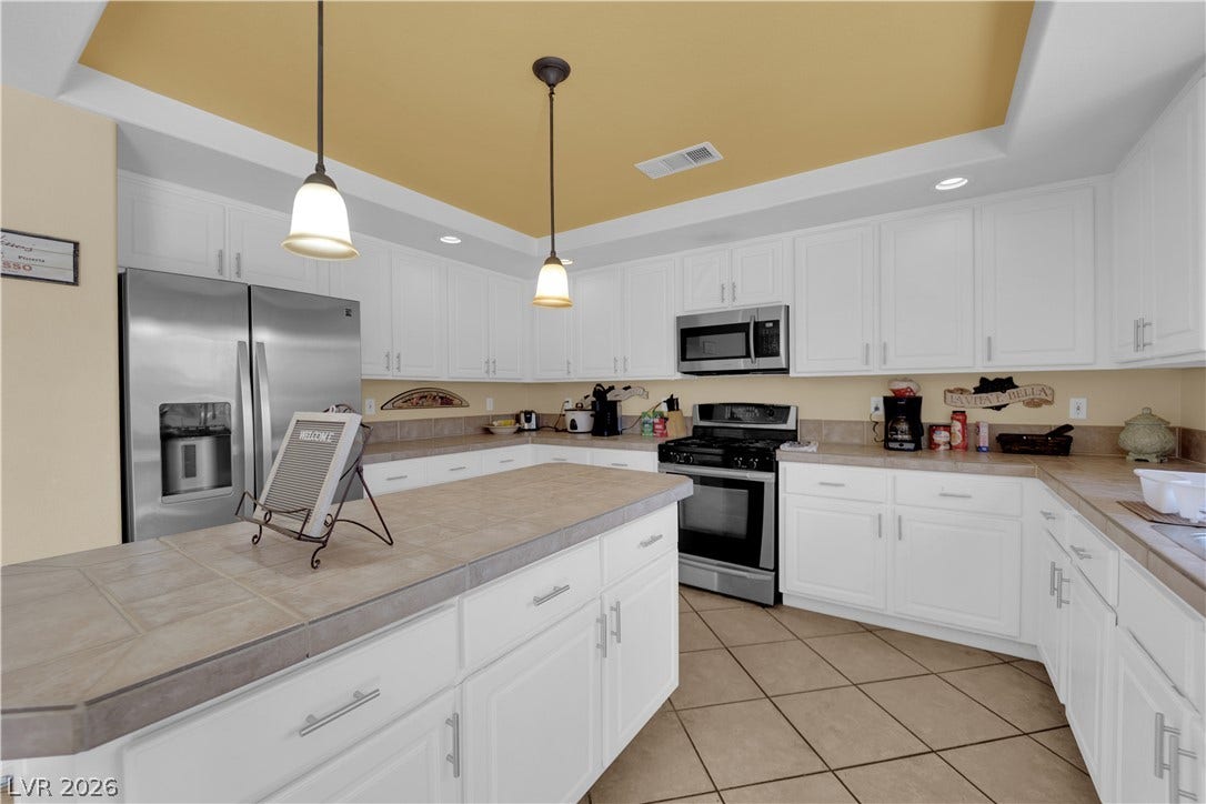 9852 Snowy Canyon Court, Las Vegas, NV 89183 Tiled flooring and matching countertops anchor this well-appointed culinary space with a central island.