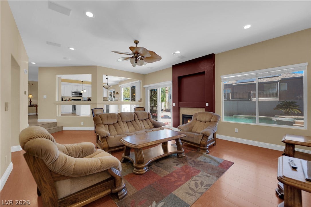 9852 Snowy Canyon Court, Las Vegas, NV 89183 Rich wood flooring anchors this open living space featuring a modern fireplace and pool views.