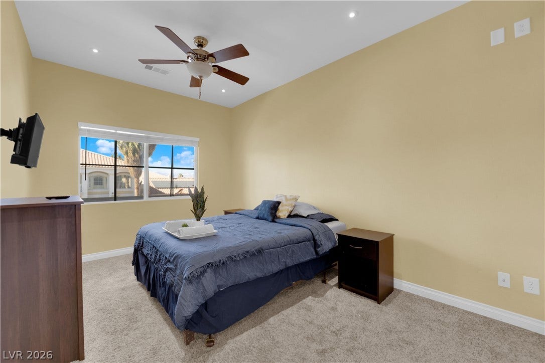 9852 Snowy Canyon Court, Las Vegas, NV 89183 Plush carpeting anchors this inviting bedroom illuminated by recessed lighting and a wide window.