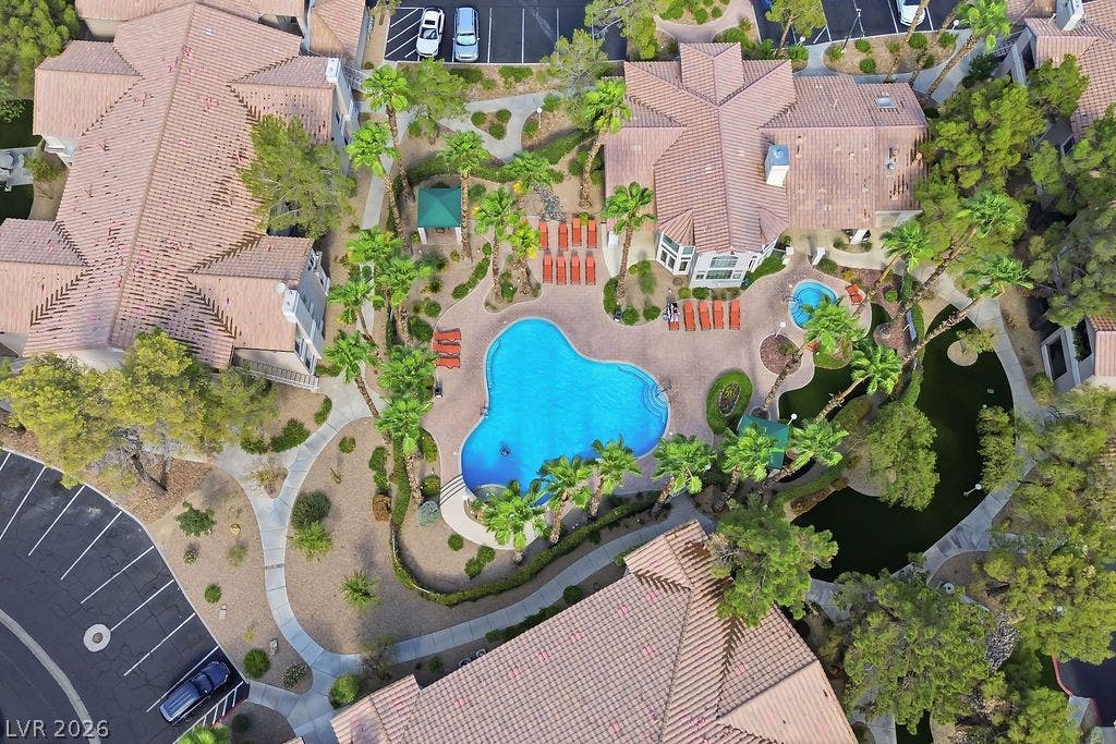 75 N Valle Verde Drive, #311, Henderson, NV 89074 A resort-style swimming pool and adjacent spa are surrounded by tropical landscaping and palm trees.