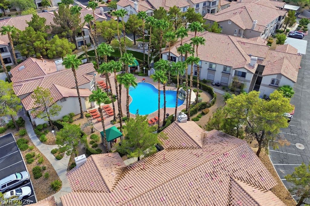 75 N Valle Verde Drive, #311, Henderson, NV 89074 Lush palm trees surround a sparkling blue swimming pool nestled within a residential community.