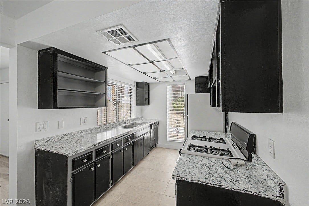 1405 Vegas Valley Drive, #187, Las Vegas, NV 89169 Striking dark cabinetry pairs with patterned countertops in this functional, well-lit kitchen space.