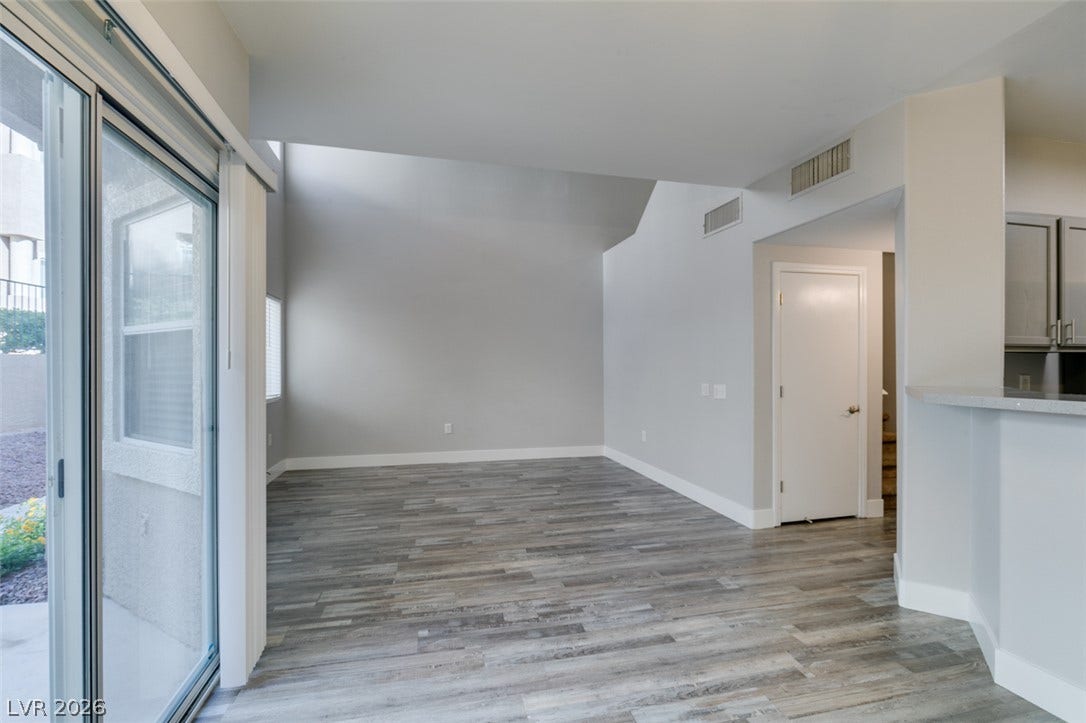 2001 Jade Creek Street, #105, Las Vegas, NV 89117 Sunlight streams through large sliding glass doors into a versatile living space with wood-look flooring.