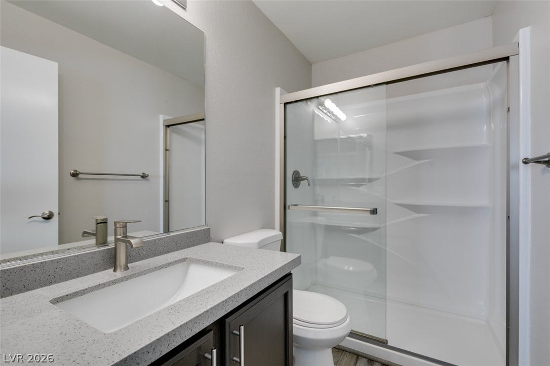 2001 Jade Creek Street, #105, Las Vegas, NV 89117 Modern stone countertops and a glass-enclosed shower highlight this sleek bathroom space.