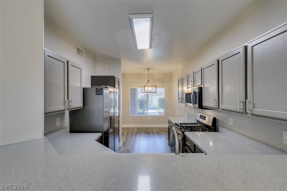 2001 Jade Creek Street, #105, Las Vegas, NV 89117 Gleaming stone countertops and modern cabinetry frame this open galley-style culinary space.