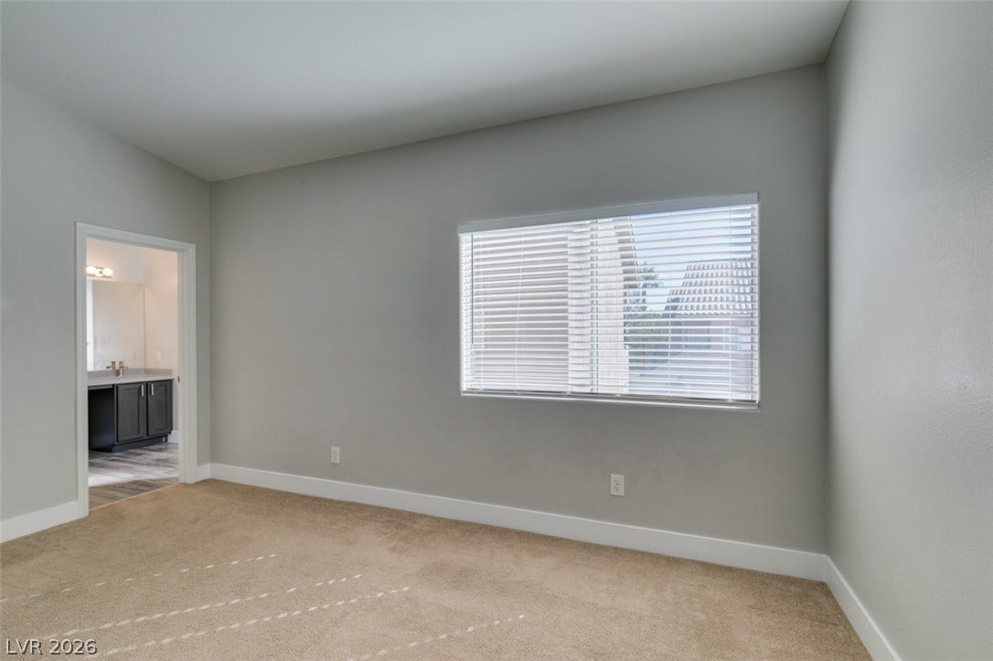 2001 Jade Creek Street, #105, Las Vegas, NV 89117 A spacious secondary bedroom features clean baseboards, neutral carpeting, and an adjacent bathroom entry.