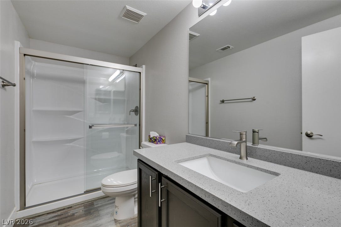 2001 Jade Creek Street, #105, Las Vegas, NV 89117 Modern finishes define this streamlined bathroom with a quartz-topped vanity and walk-in shower.