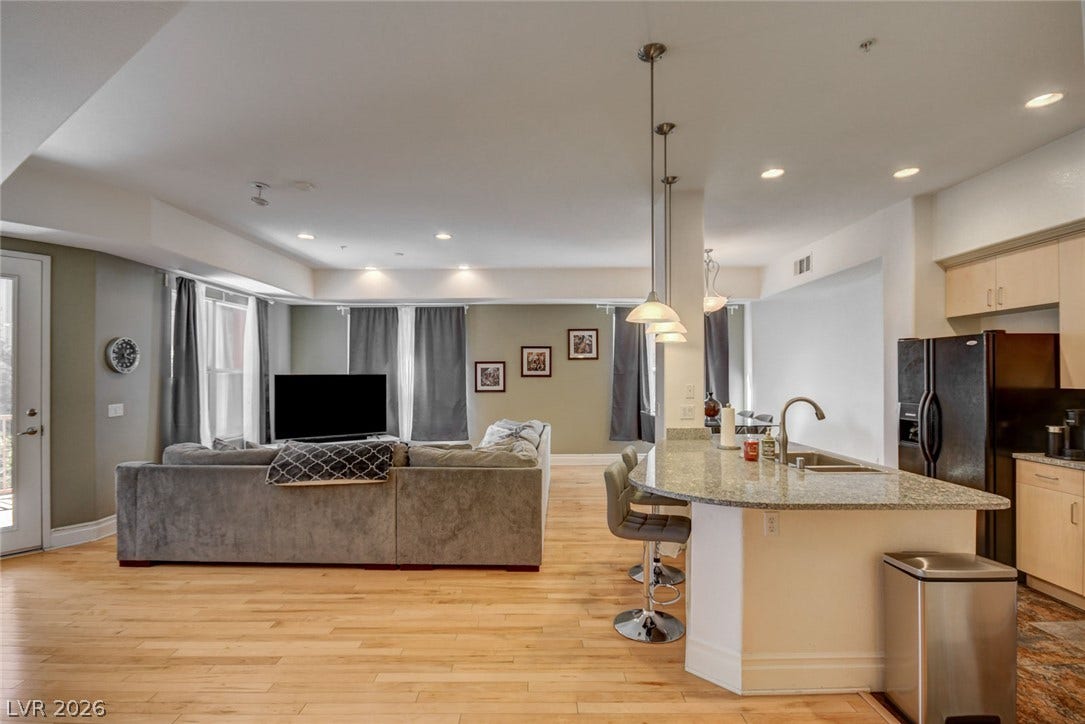 Gleaming hardwood floors and a spacious granite breakfast bar anchor this open-concept main living space.