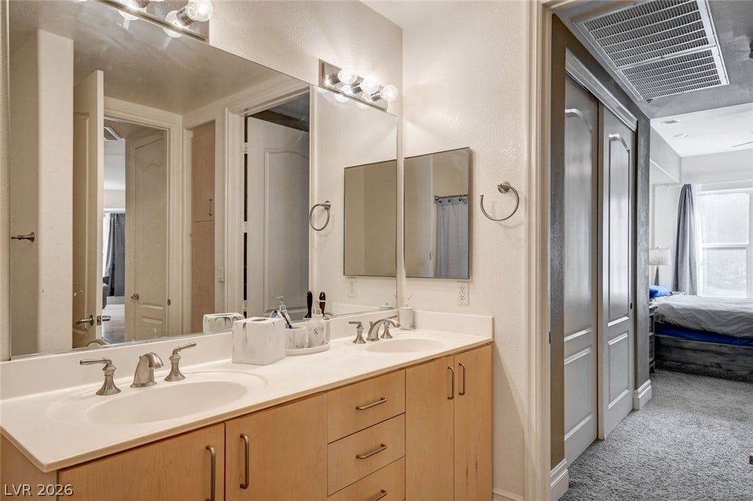 Double sinks and matching cabinetry provide clean functionality in this well-organized bathroom setup.