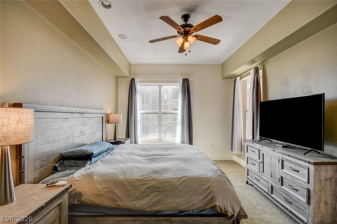A spacious bedroom features elevated ceilings.