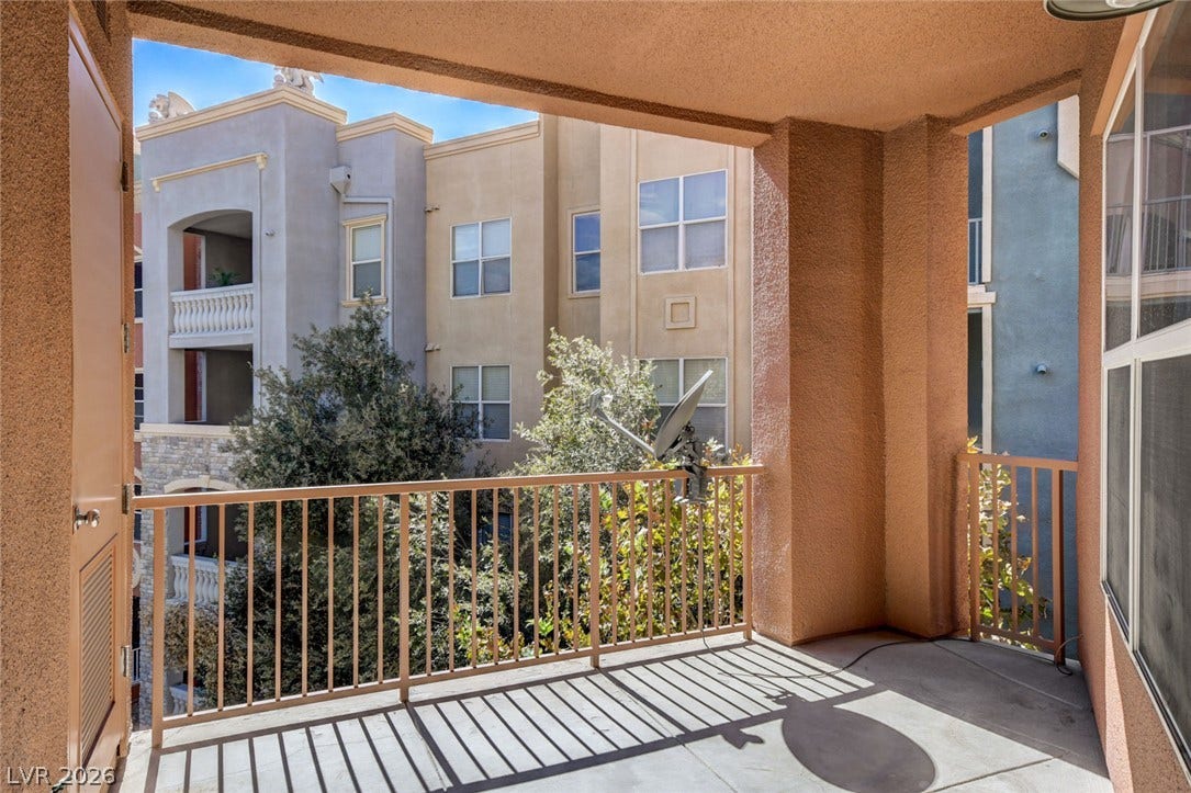 A private covered balcony overlooks the surrounding neighborhood scenery.
