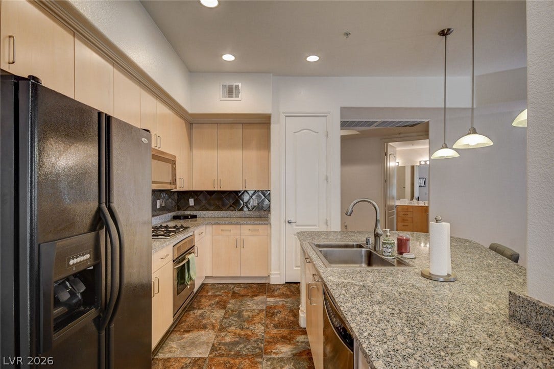 Ample wooden cabinetry and stone countertops define this functional culinary workspace.
