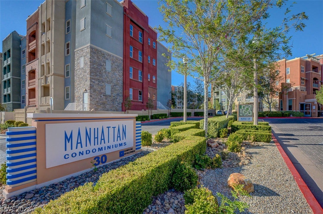 Manicured hedges frame the entrance to this multi-story contemporary residential community.