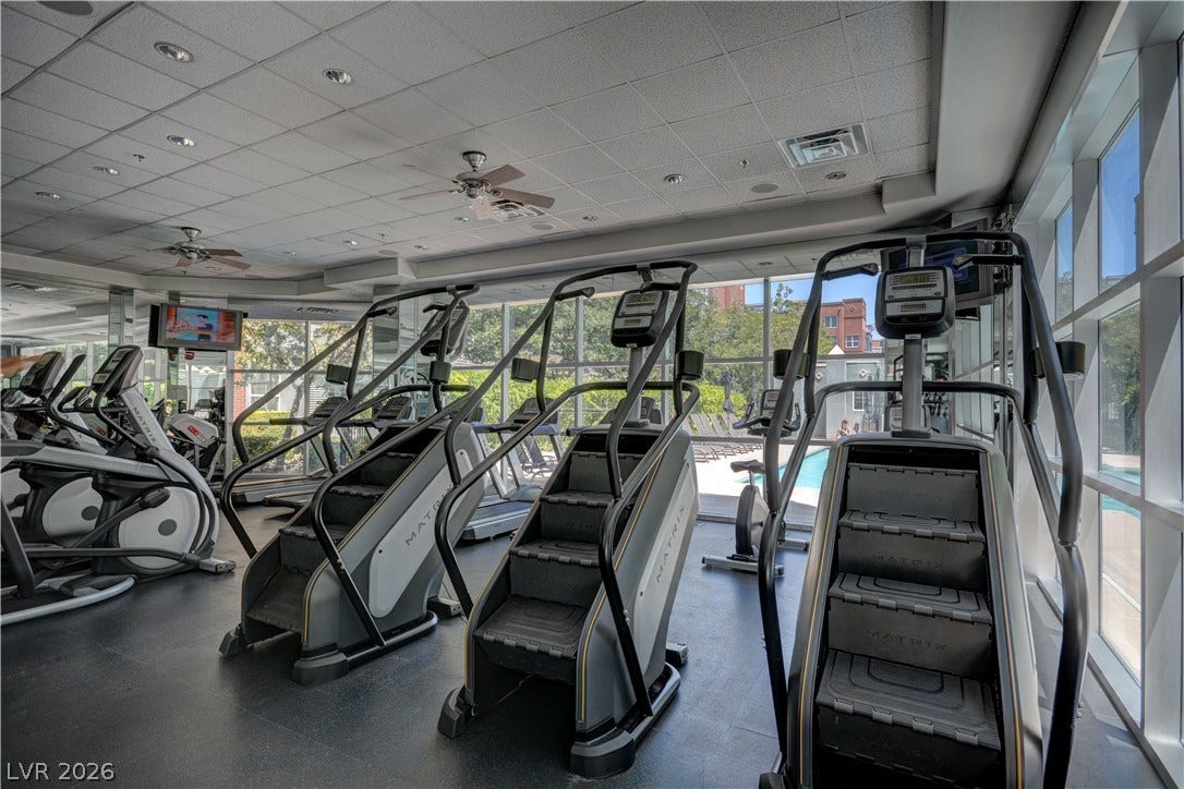 Floor-to-ceiling windows fill the workout space with light while overlooking the pool.