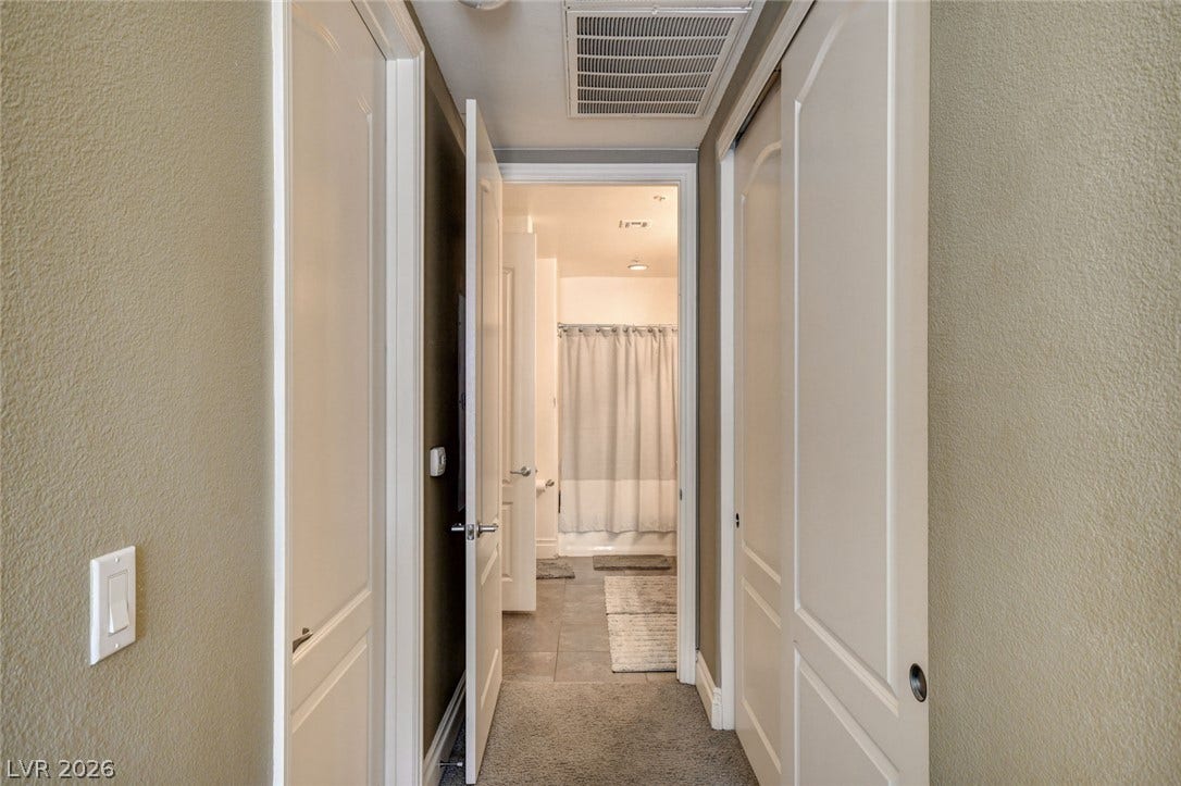 Crisp white trim and matching doors line a transitional hallway leading to an adjoining bathroom.