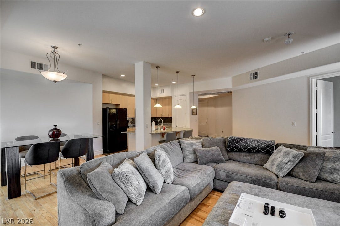 Polished hardwood flooring flows seamlessly through an open living area into a modern kitchen.