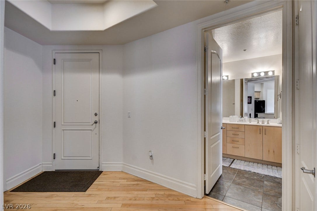 A welcoming entryway features rich hardwood flooring and leads directly to a nearby bathroom.