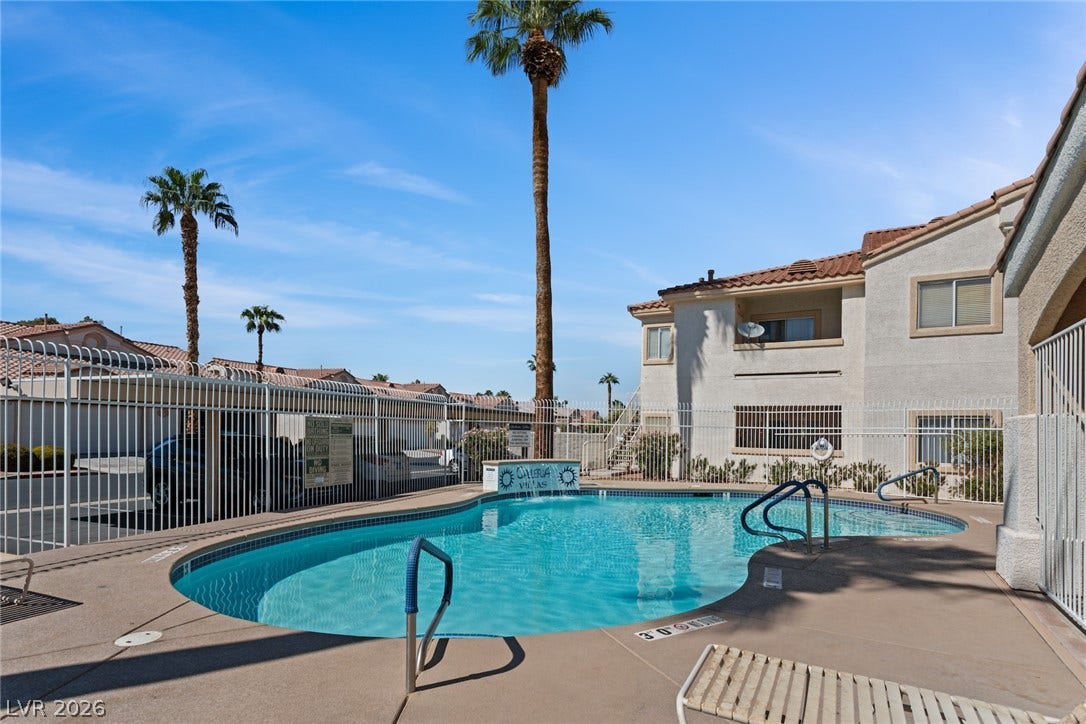 855 N Stephanie Street, #2615, Henderson, NV 89014 A secured community swimming pool sits beneath soaring palm trees and clear blue skies.