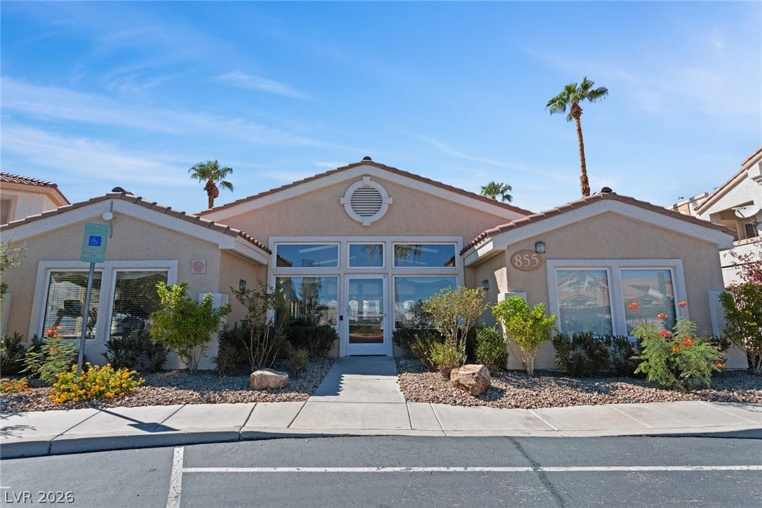 855 N Stephanie Street, #2615, Henderson, NV 89014 A classic stucco exterior features tiled roofing and symmetric window placement under blue skies.