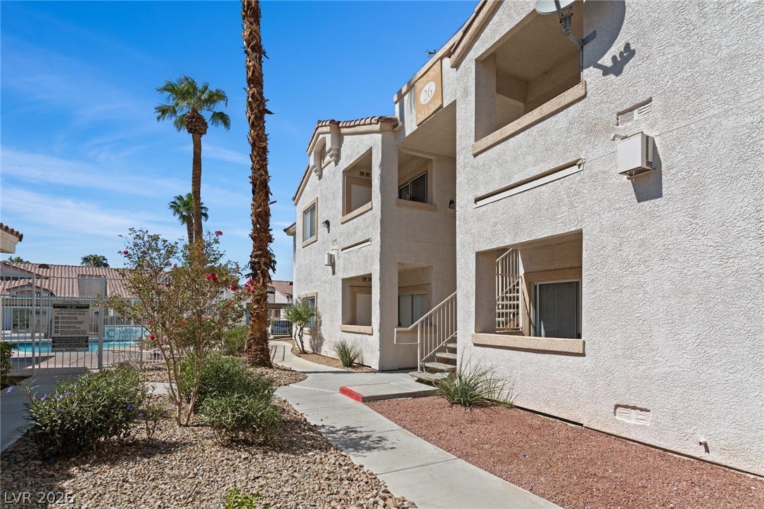 855 N Stephanie Street, #2615, Henderson, NV 89014 A concrete walkway winds through desert landscaping past the multi-level stucco exterior.