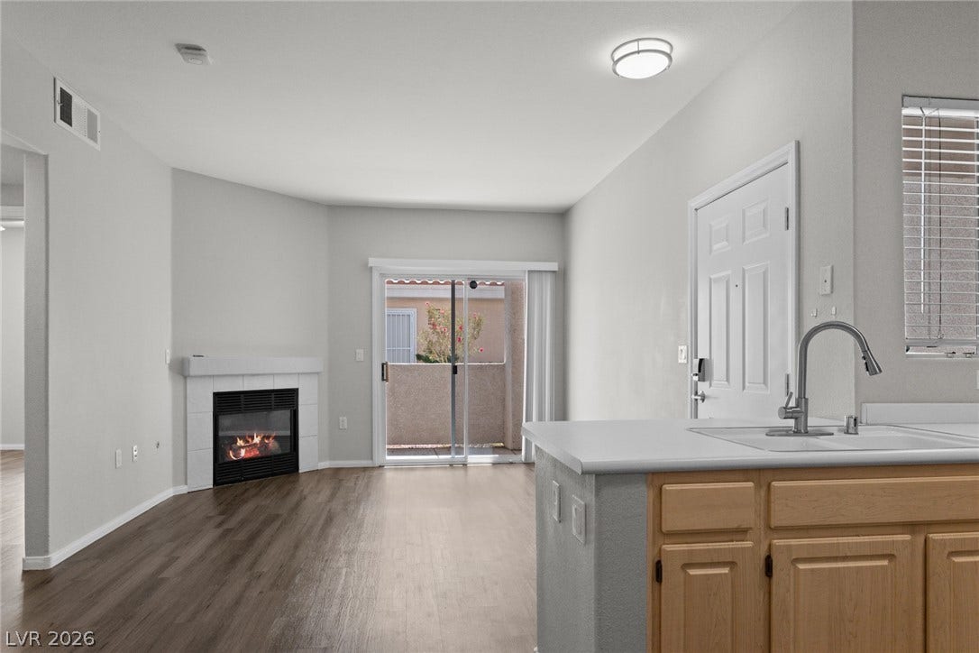 855 N Stephanie Street, #2615, Henderson, NV 89014 A cozy fireplace warms this open living space featuring wood-look flooring and sliding glass doors.