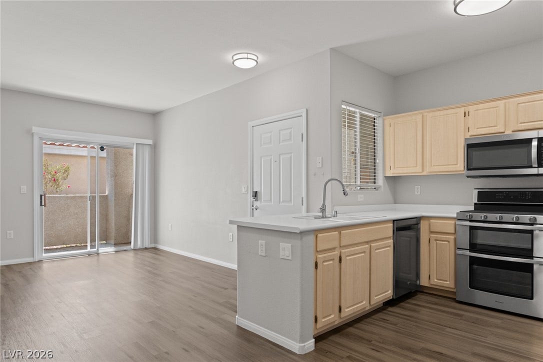 855 N Stephanie Street, #2615, Henderson, NV 89014 Smooth wood-look flooring anchors this open-plan kitchen and living space featuring sliding glass doors.