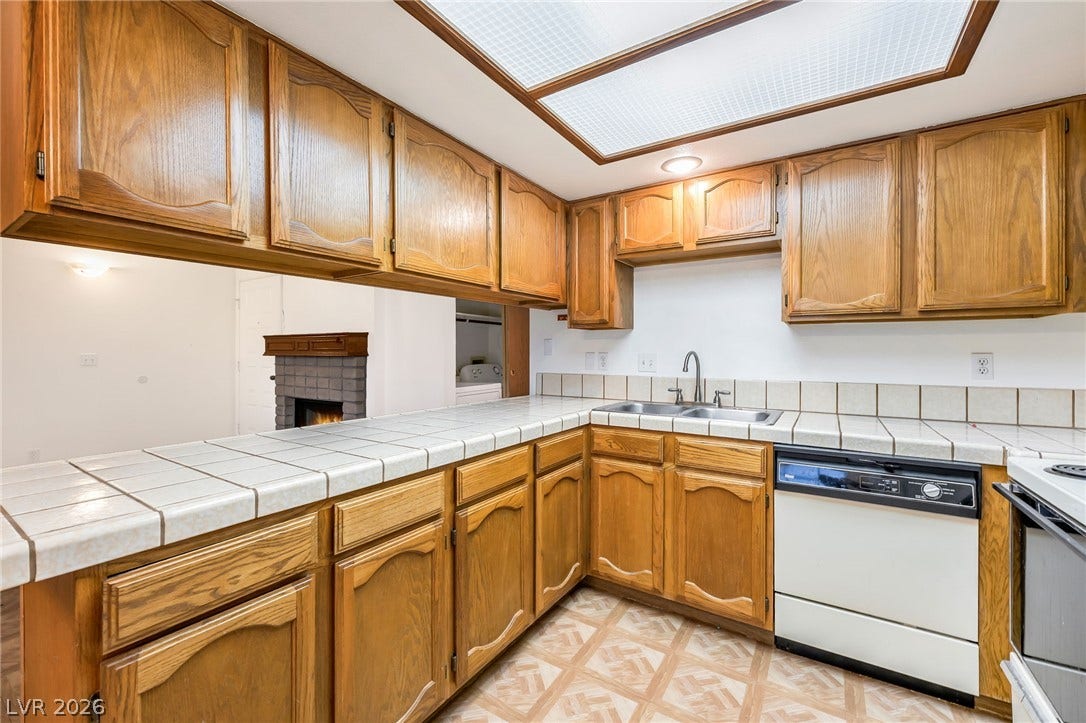4340 Sanderling Circle, #78, Las Vegas, NV 89103 Rich wood cabinetry and classic tiled countertops define this functional, light-filled kitchen space.