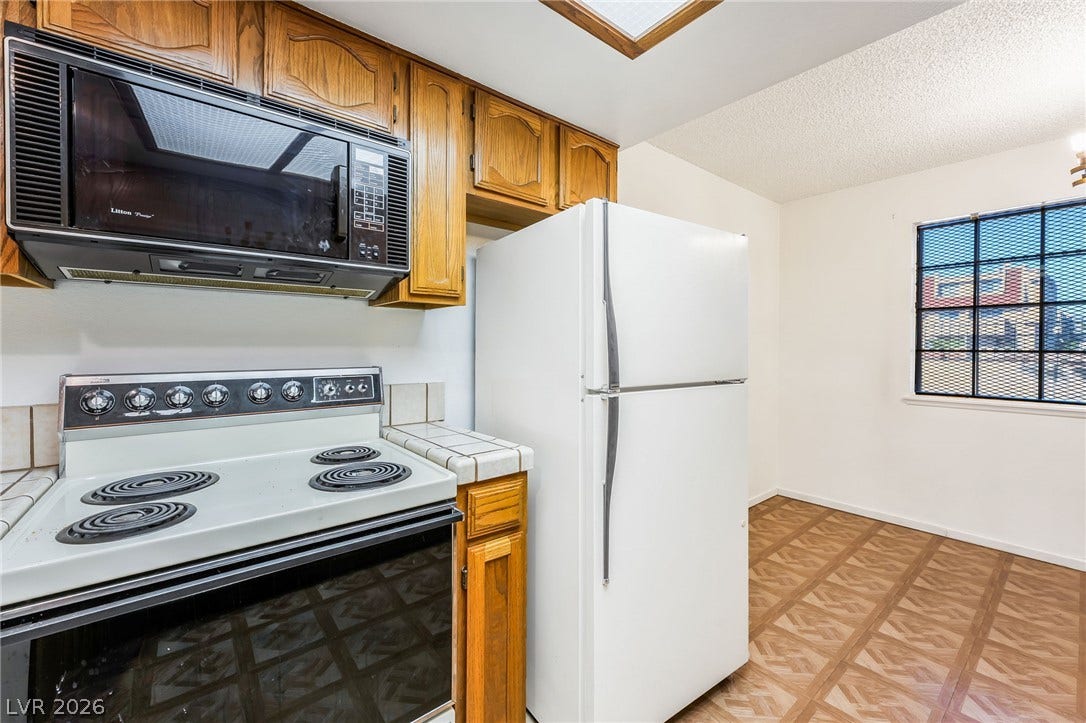 4340 Sanderling Circle, #78, Las Vegas, NV 89103 Classic wooden cabinetry and patterned flooring define this functional kitchen space.