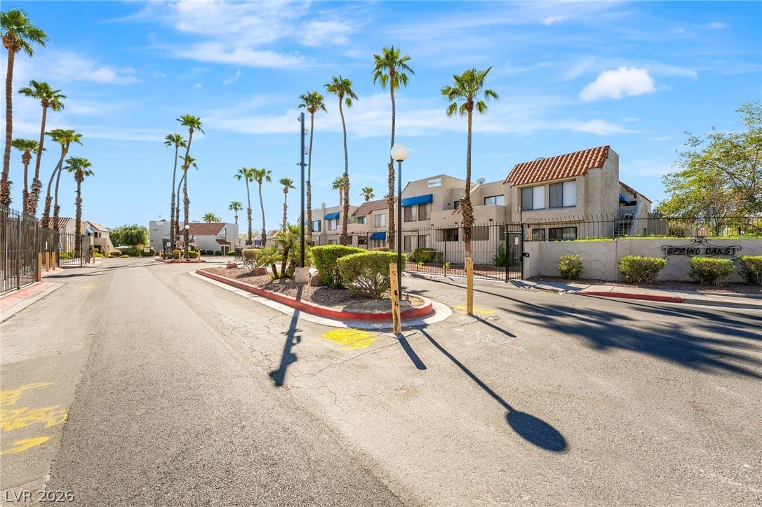 4340 Sanderling Circle, #78, Las Vegas, NV 89103 Gated neighborhood entrance features stucco architecture, tile roofs, and mature palm trees.