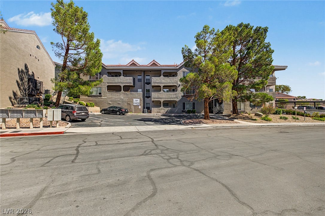 701 Capri Drive, #10B, Boulder City, NV 89005 Mature trees frame the multi-level stucco facade of this modern residential complex.