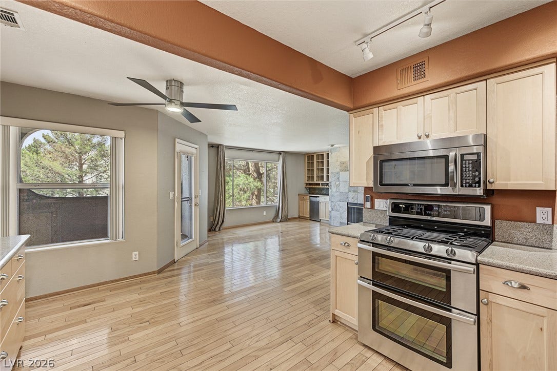 701 Capri Drive, #10B, Boulder City, NV 89005 Polished hardwood floors flow through this open-concept kitchen and dining area with large windows.