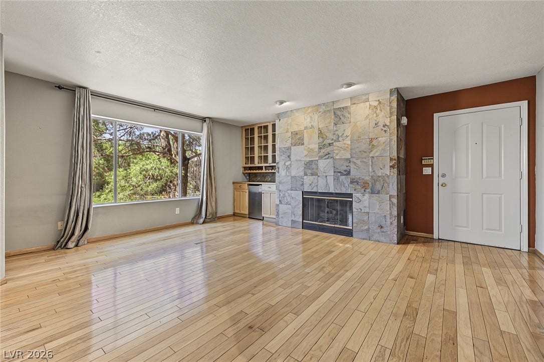 701 Capri Drive, #10B, Boulder City, NV 89005 Polished hardwood floors and a floor-to-ceiling stone fireplace create a warm, inviting living space.