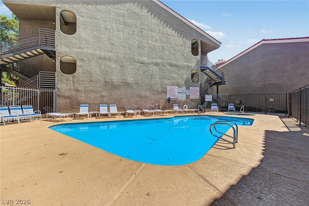 701 Capri Drive, #10B, Boulder City, NV 89005 A fenced swimming pool patio sits adjacent to the multi-story stucco residential structures.