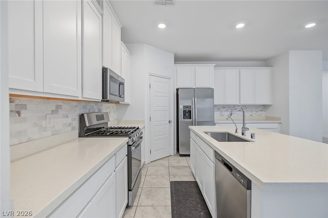 2728 Lindsey Springs Street, Las Vegas, NV 89142 Sleek stone countertops and pristine white cabinetry define this modern culinary workspace.