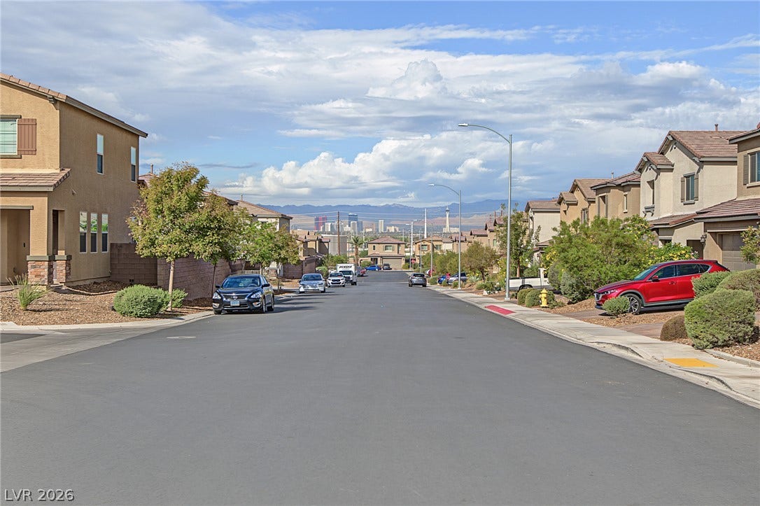 2728 Lindsey Springs Street, Las Vegas, NV 89142 Distal city skyline and mountain views frame this quiet suburban streetscape lined with modern homes.