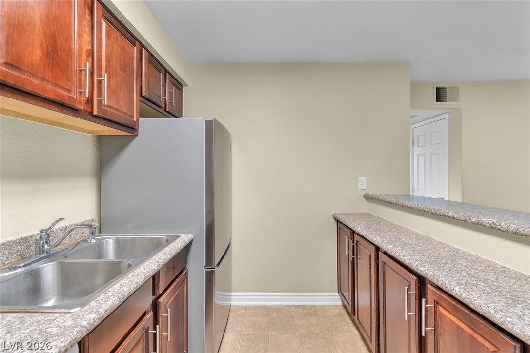Rich wood cabinetry paired with stone countertops defines this functional kitchen workspace.