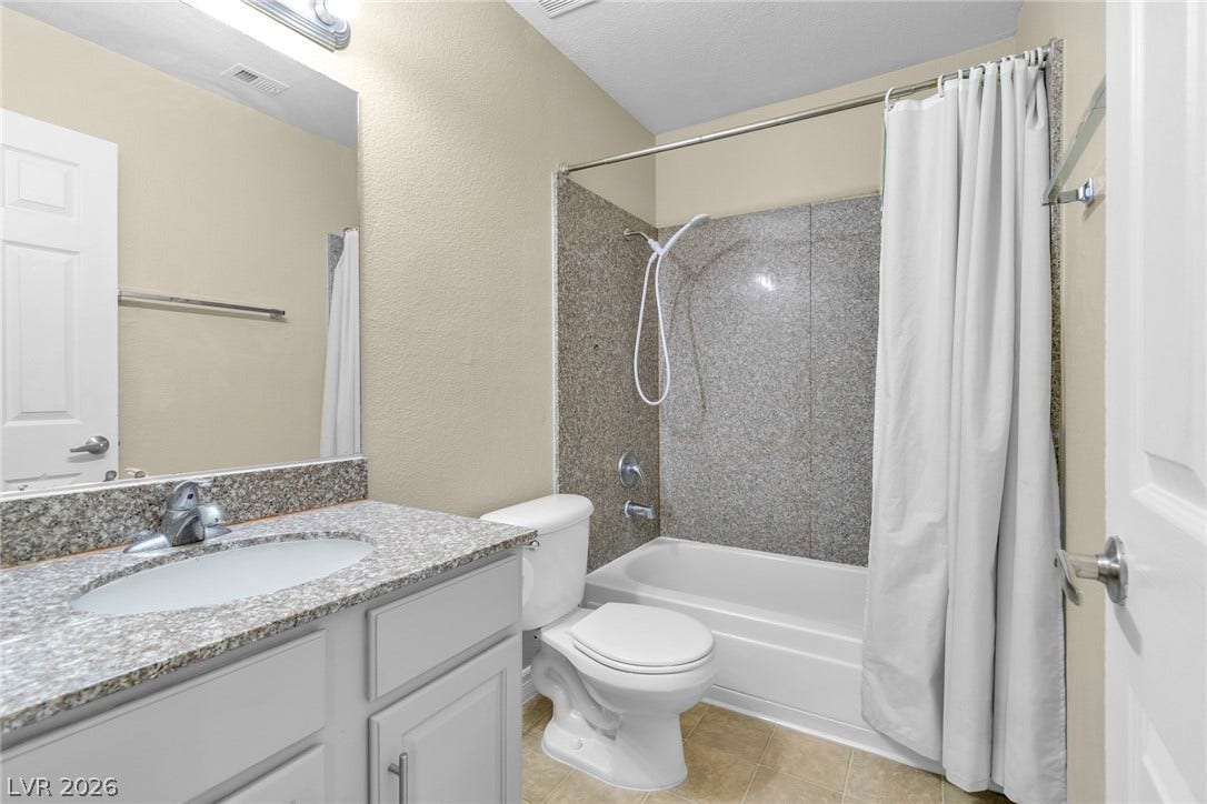Polished stone counters and clean tile flooring define this functional bathroom space.
