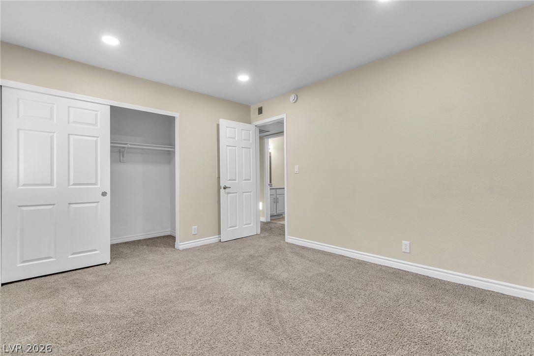 A spacious bedroom features plush carpeting, recessed lighting, and a walk-in closet.