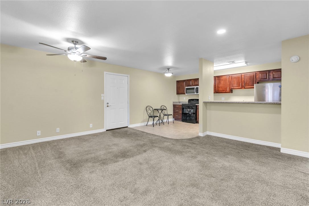 Plush carpeting transitions into a tiled kitchen space with an open breakfast bar layout.