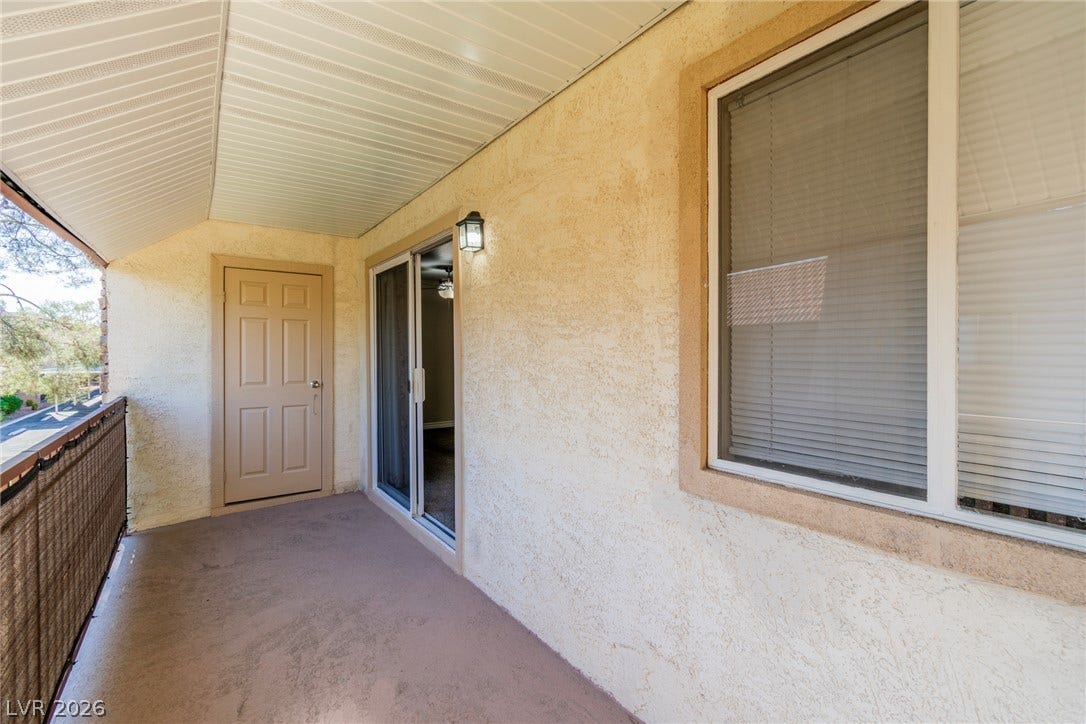 A covered private balcony features textured stucco walls and direct access through sliding doors.