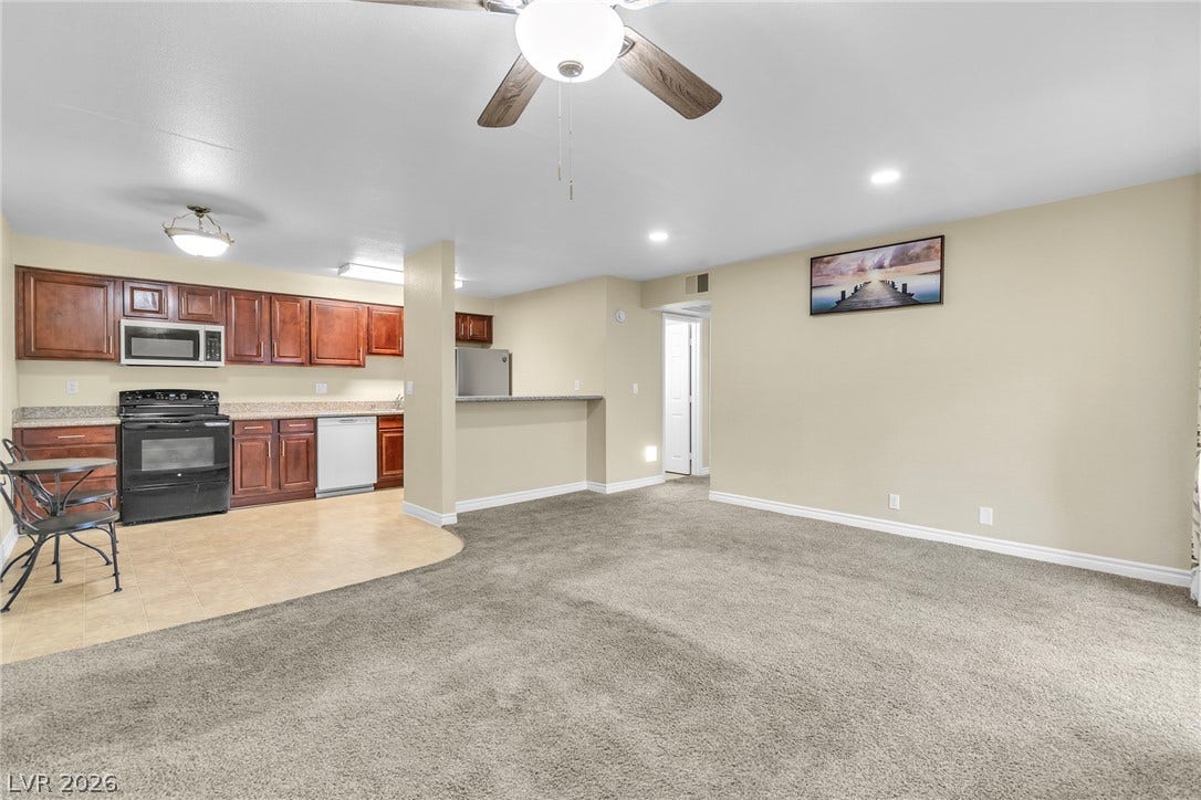 Plush carpeting transitions smoothly into a tiled kitchen space with rich wood cabinetry.