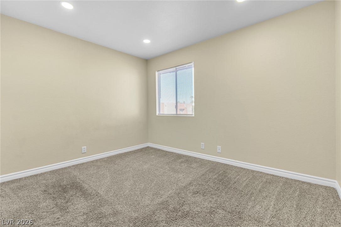 Plush carpeting and recessed lighting create a comfortable atmosphere in this versatile bedroom.