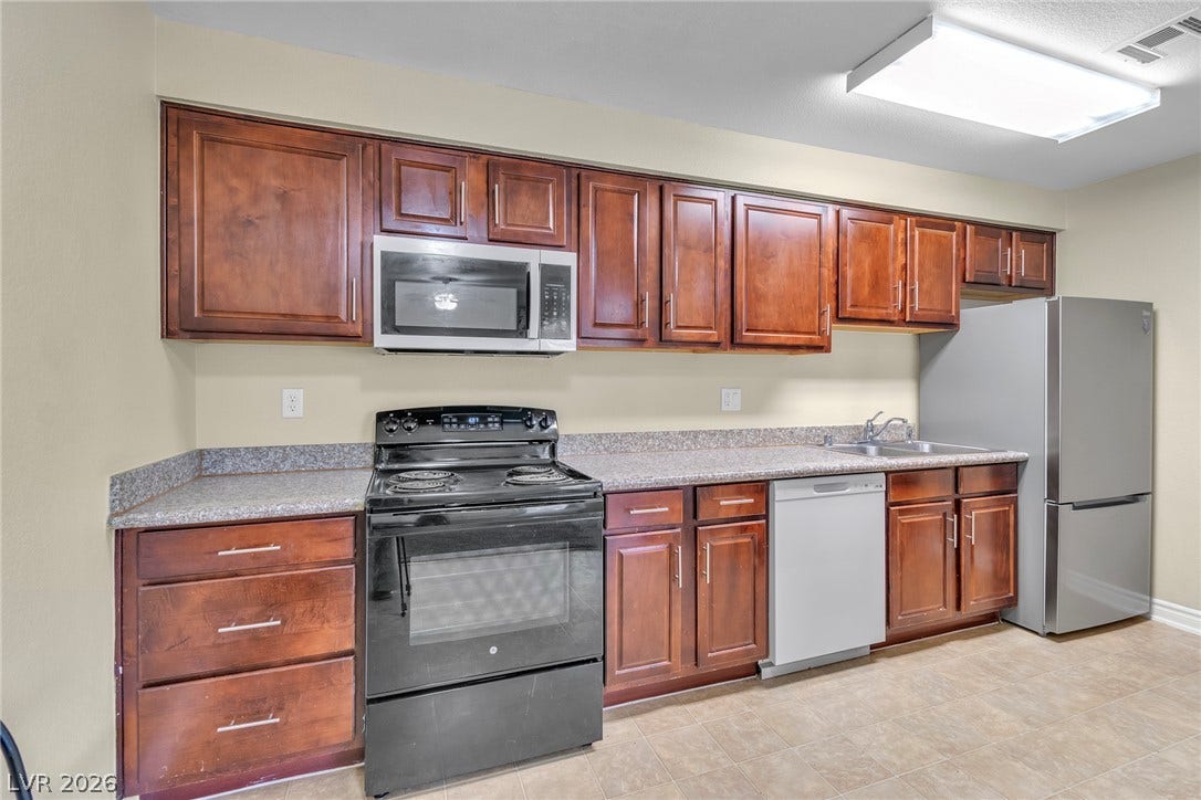 Rich wood cabinetry provides ample storage across durable countertops in this functional kitchen.