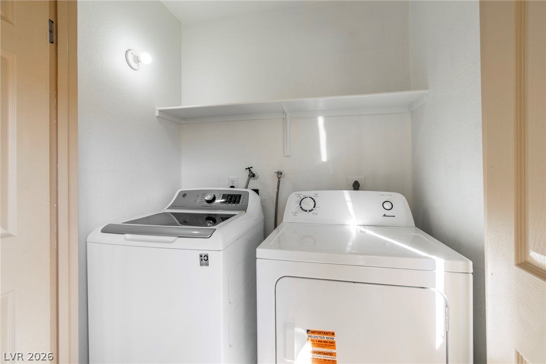 Functional laundry space equipped with overhead shelving and hookups for convenience.